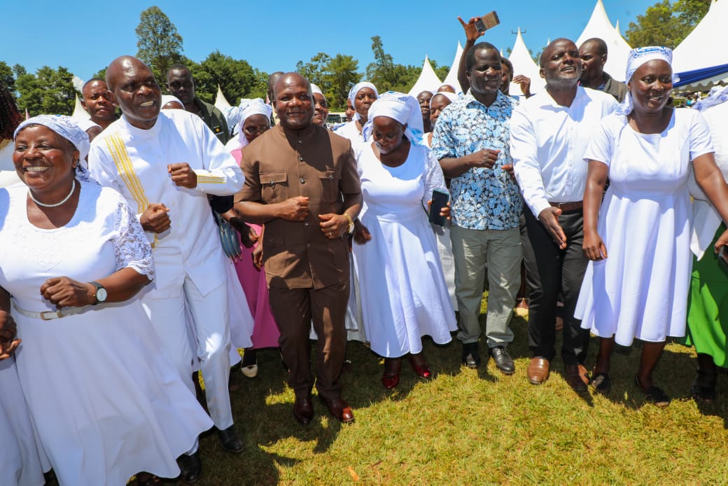 Governor Fernandez Barasa, dressed in a brown suit, joins the USFW faithful in a praise session during their prayer meeting at Chevaywa Primary School, as reported by Wakhungu Andanje.